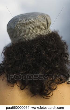 Young woman with curly hair wearing cap, rear view View Large Photo Image Picture - Young woman with curly hair wearing cap, rear view. Fotosearch