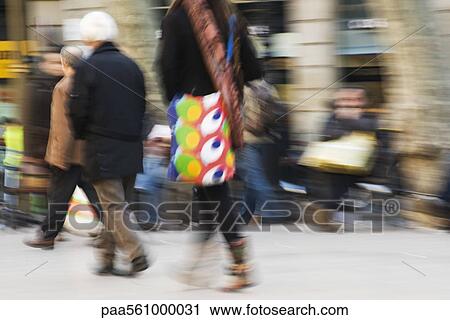 Stock Image - Pedestrians walking on sidewalk, blurred. Fotosearch