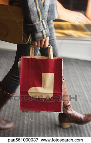 Stock Photo - Shopper carrying shopping bag with Christmas stocking on it, cropped. Fotosearch