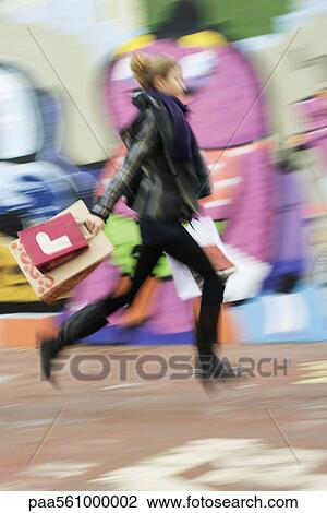 Stock Image - Teenage girl walking with shopping bags, blurred. Fotosearch