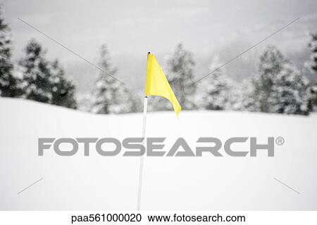 Stock Image - Yellow flag on snow-covered golf course. Fotosearch