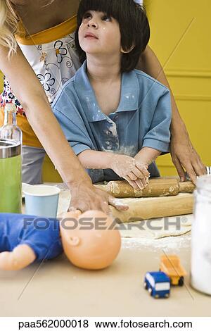Stock Photo - Boy rolling out dough with mother, cropped. Fotosearch