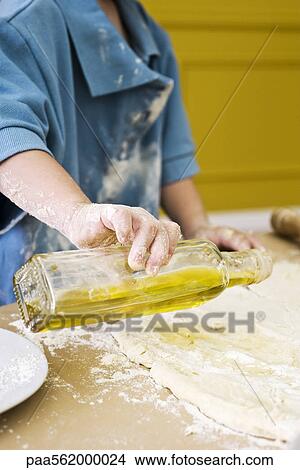Child pouring olive oil on rolled out dough, cropped View Large Photo Image Picture - Child pouring olive oil on rolled out dough, cropped. Fotosearch