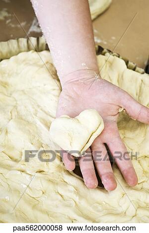 Stock Photo - Child's hand holding heart shaped piece of dough. Fotosearch
