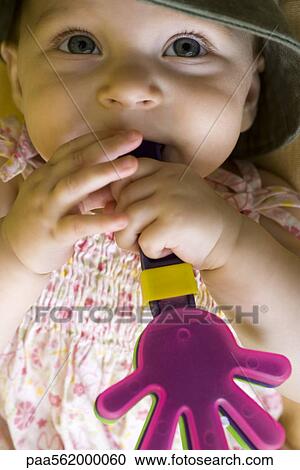Stock Image - Infant chewing on plastic toy. Fotosearch