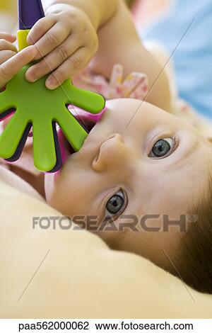 Infant girl chewing on plastic toy, looking at camera View Large Photo Image Stock Image - Infant girl chewing on plastic toy, looking at camera. Fotosearch