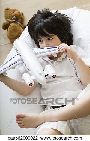 Little boy lying on beanbag chair, playing with toy airplane View Large Photo Image Stock Image - Little boy lying on beanbag chair, playing with toy airplane. Fotosearch