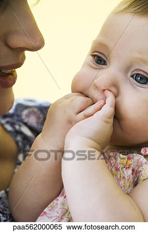 Mother holding infant with fingers in mouth View Large Photo Image Stock Photography - Mother holding infant with fingers in mouth. Fotosearch