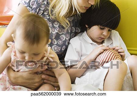 Mother holding son and infant daughter on lap, boy sulking, cropped View Large Photo Image Stock Photo - Mother holding son and infant daughter on lap, boy sulking, cropped. Fotosearch