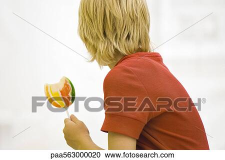 Boy holding lollipop looking away View Large Photo Image Stock Image - Boy holding lollipop looking away. Fotosearch