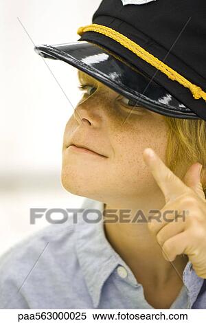 Stock Photography - Boy wearing police officer's hat pointing at camera. Fotosearch