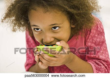 Picture - Girl eating candy. Fotosearch