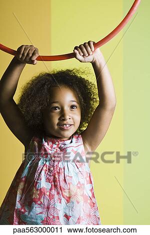 Little girl holding plastic hoop above her head View Large Photo Image Stock Image - Little girl holding plastic hoop above her head. Fotosearch
