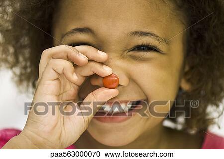 Little girl holding up piece of candy View Large Photo Image Stock Image - Little girl holding up piece of candy. Fotosearch