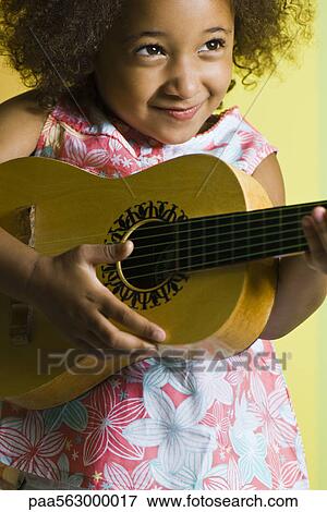 Stock Photo - Little girl playing small guitar. Fotosearch