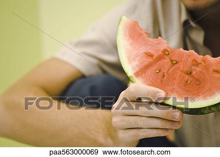 Man holding slice of watermelon, cropped View Large Photo Image Stock Photo - Man holding slice of watermelon, cropped. Fotosearch