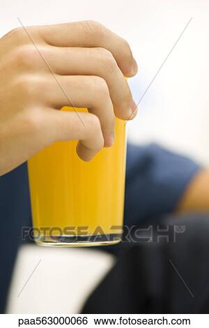 Person holding glass of orange juice, cropped View Large Photo Image Stock Photograph - Person holding glass of orange juice, cropped. Fotosearch
