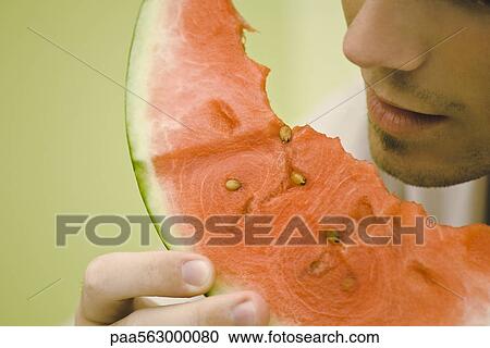 Stock Image - You man eating slice of watermelon. Fotosearch
