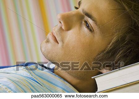 Young man daydreaming, resting head on stack of books View Large Photo Image Stock Photography - Young man daydreaming, resting head on stack of books. Fotosearch