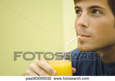 Stock Image - Young man drinking orange juice. Fotosearch