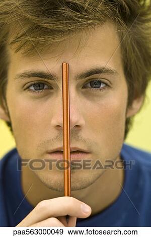 Young man holding pencil up to forehead View Large Photo Image Stock Photo - Young man holding pencil up to forehead. Fotosearch