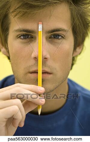 Young man holding up pencil View Large Photo Image Stock Image - Young man holding up pencil. Fotosearch