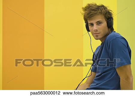 Stock Image - Young man listening to headphones. Fotosearch