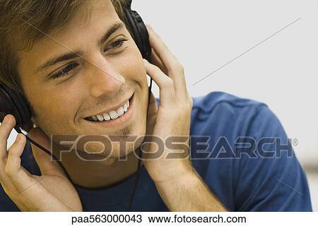 Young man listening to headphones View Large Photo Image Stock Image - Young man listening to headphones. Fotosearch