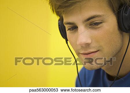 Young man listening to headphones View Large Photo Image Stock Image - Young man listening to headphones. Fotosearch