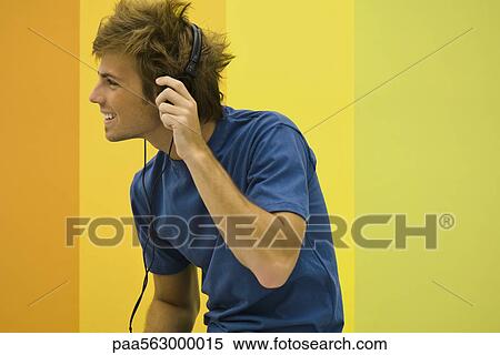 Young man listening to headphones View Large Photo Image Stock Photography - Young man listening to headphones. Fotosearch