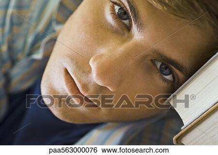 Young man resting head on books, portrait View Large Photo Image Stock Photograph - Young man resting head on books, portrait. Fotosearch