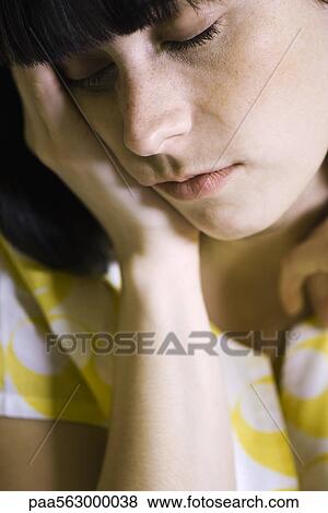 Stock Photo - Young woman holding head, eyes closed. Fotosearch