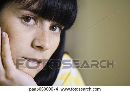Young woman resting chin on hand, biting lip, portrait View Large Photo Image Picture - Young woman resting chin on hand, biting lip, portrait. Fotosearch