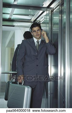 Stock Photo - Businessman in elevator using cell phone. Fotosearch