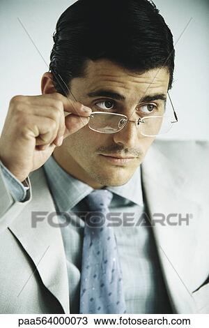 Businessman looking away, lowering glasses, portrait View Large Photo Image Stock Image - Businessman looking away, lowering glasses, portrait. Fotosearch