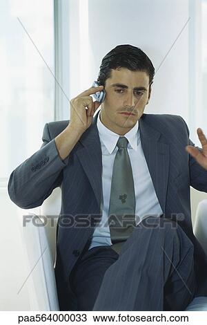 Businessman sitting with legs crossed using cell phone View Large Photo Image Stock Image - Businessman sitting with legs crossed using cell phone. Fotosearch