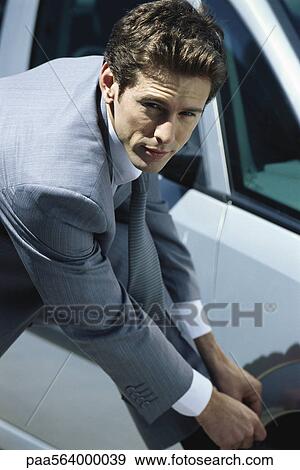 Stock Photo - Businessman tying shoe, looking up at camera. Fotosearch