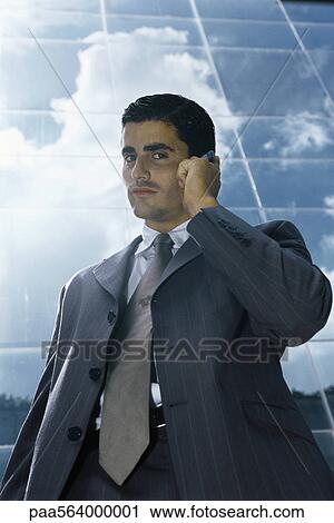 Stock Image - Businessman using cell phone outside office building. Fotosearch