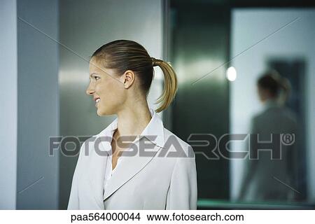 Businesswoman emerging from elevator, looking away smiling View Large Photo Image Picture - Businesswoman emerging from elevator, looking away smiling. Fotosearch