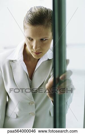 Stock Photograph - Businesswoman entering building, hesitating at doorway. Fotosearch