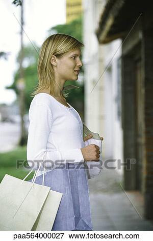 Woman carrying shopping bags on arm window shopping, side view View Large Photo Image Stock Photo - Woman carrying shopping bags on arm window shopping, side view. Fotosearch