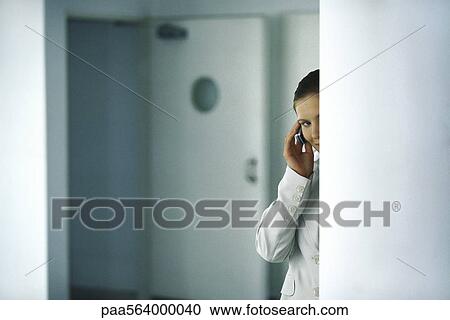 Woman standing behind column discretely speaking on cell phone View Large Photo Image Stock Image - Woman standing behind column discretely speaking on cell phone. Fotosearch