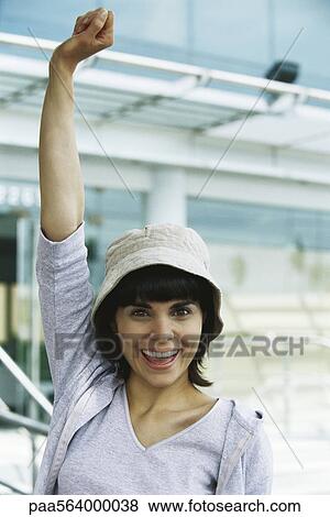 Stock Photo - Young woman smiling at camera with one fist raised in air. Fotosearch