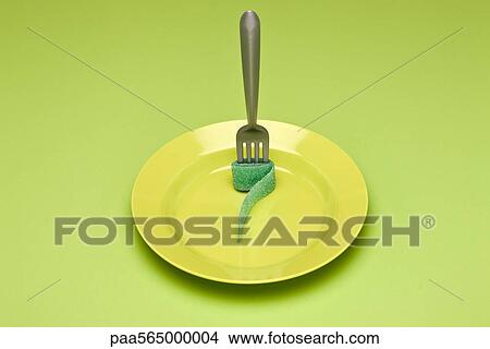 Picture - Food concept, fork with rolled up gummy candy strip on plate, resembling noodle. Fotosearch