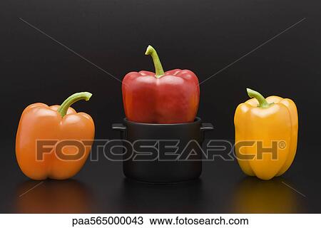 Stock Image - Fresh bell peppers, one squeezed into miniature pot. Fotosearch