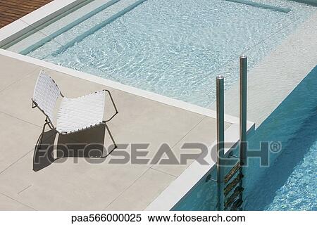 Chair at edge of pool near ladder View Large Photo Image Stock Photography - Chair at edge of pool near ladder. Fotosearch