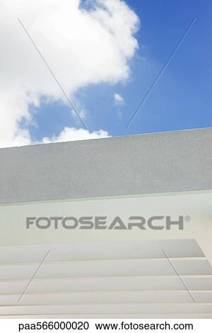 Stock Image - Cloud against blue sky above building wall. Fotosearch