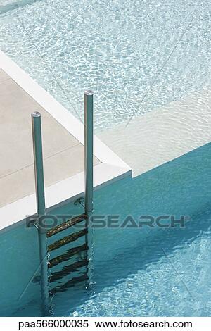 Stock Photography - Swimming pool ladder at deep end separated from shallow pool by ledge. Fotosearch