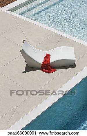 Stock Image - Towel left on poolside deckchair. Fotosearch