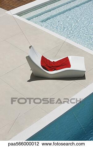 Stock Image - Towel left on poolside deckchair. Fotosearch